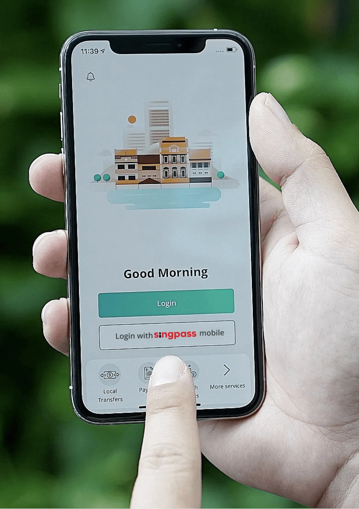 A hand holding a phone with the OCBC app home screen, including the button "Login with Singpass app"